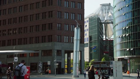 May, 2017 Berlin, Germany. Wide Potsdamer Platz pan by modern office buildings, Sony Center with street traffic with pedestrians, cars, and sightseeing bus.