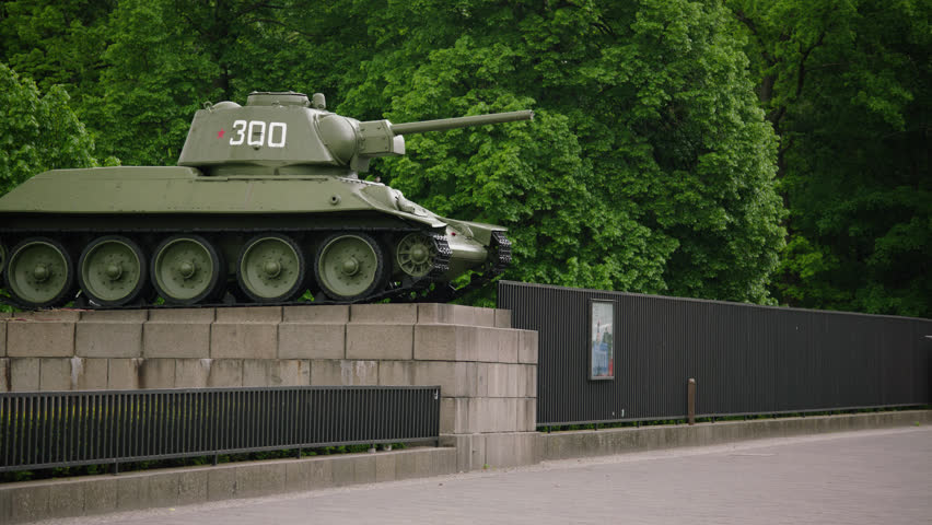 May, 2017 Berlin, Germany. Static shot of Memorial for Soviet Soldiers tank sculpture with elder couple walking on a cloudy day.