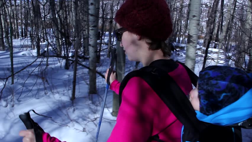 a woman and baby cross country skiing across the snow