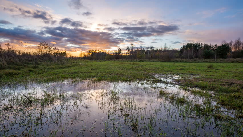 After sunset time-lapse with meadow and puddle under beautiful sky. 4k time-lapse, 3840x2160, 30fps.