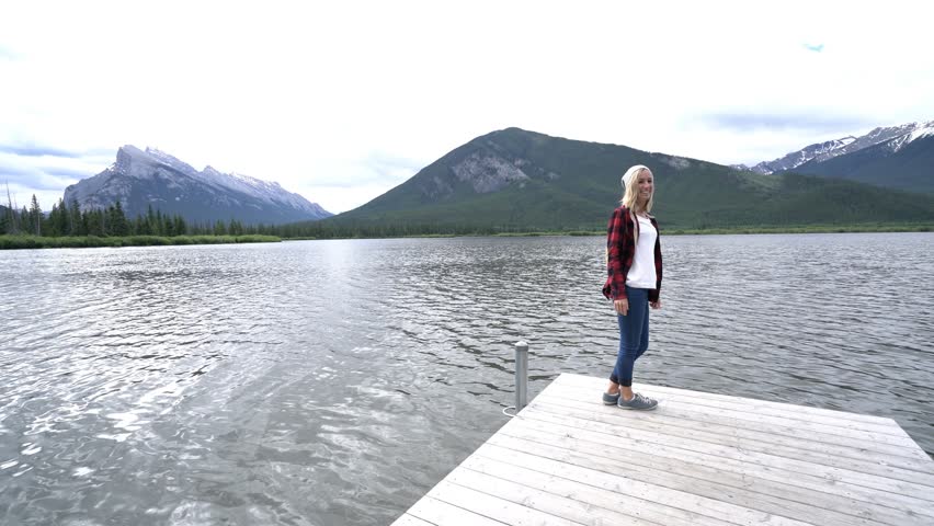 Young couple on a lake pier in Banff national park, Canada walked by the lakeshore and outstretches arms for positive emotion and success. People love travel outdoors concept