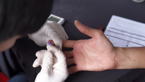 Diabetes diabetic blood test.Close up shot on doctor's hand handling glucometer for glucose sugar measuring level blood test on patient finger.