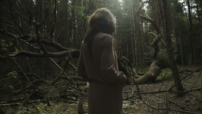 Young woman in the mistery woods standing by the fallen tree