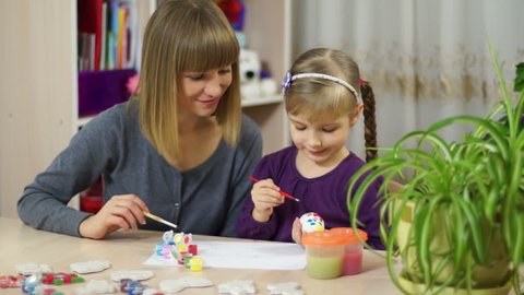 Mother and child decorate an Easter egg. Looking at camera Stock Video