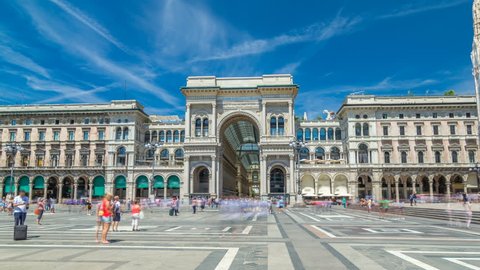 The Galleria Vittorio Emanuele II timelapse hyperlapse on the Piazza del Duomo (Cathedral Square). This gallery is tourist attraction of Milan. Blue cloudy sky at summer day. People walking on the