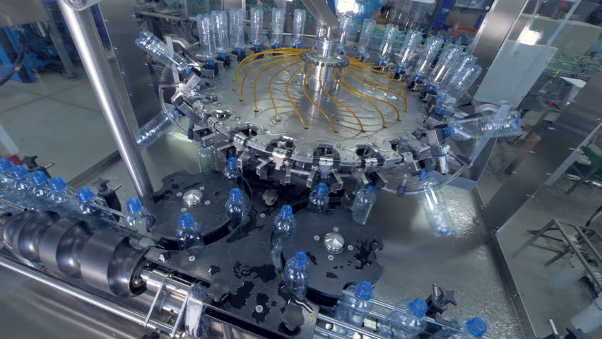 Bottles going in and out of a washer. 