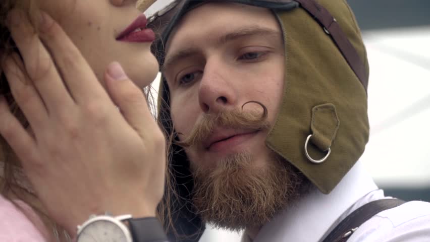 Romantic moment for a bearded pilot in a helmet and women in a pink dress