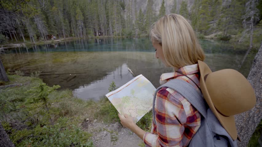 Hiker female looking at map near mountain lake 
Shot in Alberta in Canada
People travel exploration concept