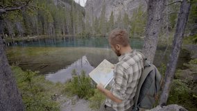 One young man hiking stops by the mountain lake to check at trail map
People traveling and enjoying outdoor activities concept
Shot in Alberta in the Canadian rockies in Canada