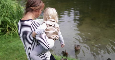 Mother and daughter feeding the ducks in park
