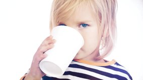 A child drinks a drink from a paper cup. Video on a light background.