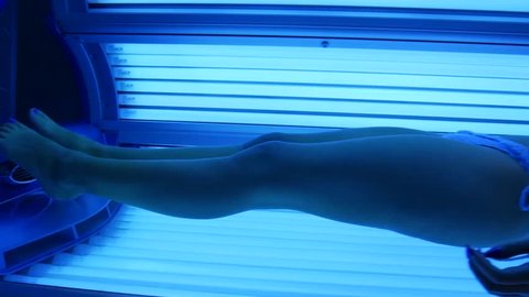 The girl is in the solarium. Young sexy woman in a bikini sunbathing.