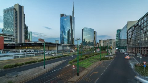 Milan skyline with modern skyscrapers in Porta Nuova business district day to night transition timelapse in Milan, Italy, after sunset. Traffic on the road. Light in windows. Top view from bridge