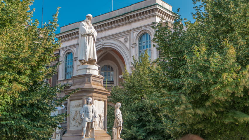 Monument to Leonardo da Vinci in Piazza della Scala (meaning La Scala square) timelapse. It designed by sculptor Pietro Magni in 1872 in Milan, Italy. Blue sky at summer day. Green trees