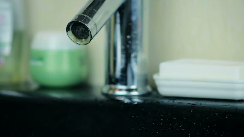 SLOW MOTION: close-up a powerful stream of water flowing from an aluminum tap in the bathroom.
