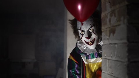 Evil Clown in Dark Scary Halloween Horror Scene, Frightening with Balloon.