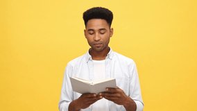 Disappointed Young african man in shirt reading book, puts a book on head and meditation over yellow background