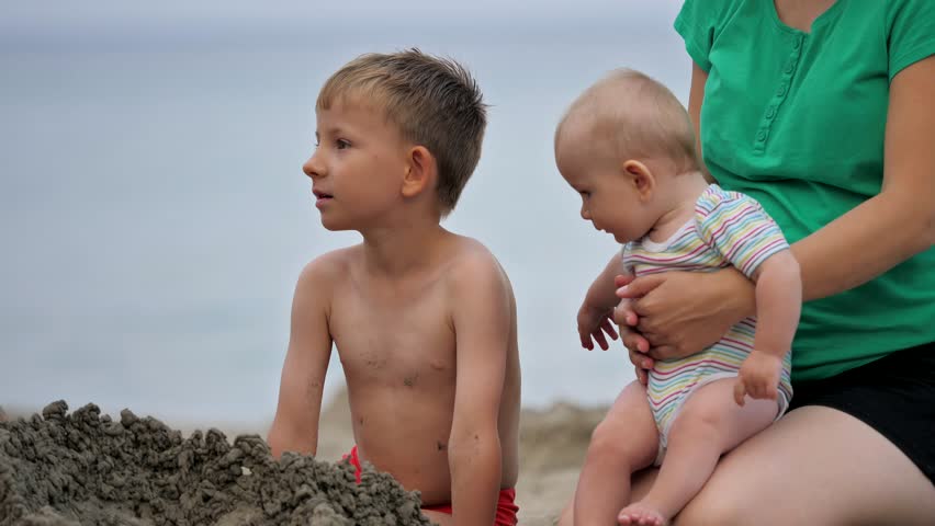 Father hand and son building a sandcastle, mother hands holding baby child, family together at seaside
