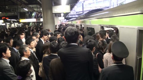 TOKYO, JAPAN - 6 NOVEMBER 2012: Handheld video of commuting passengers pushing their way into a local train at a major train station in Tokyo, Japan