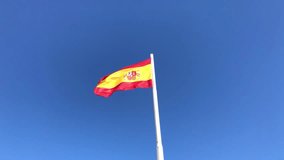Flag of Spain waving in the wind against clear blue sky background