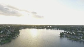 Aerial shot of a lake surrounded by homes during the sunset