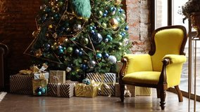 Dark room with Christmas and New Year interior decoration. Green tree decorated with toys and flashing garland and yellow chair