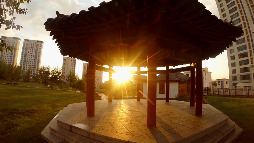 Sunlight shines through an ancient wooden building next to modern skyscrapers in the capital of Mongolia
