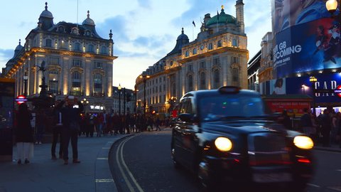 LONDON, ENGLAND, UNITED KINGDOM - APRIL, 2017: City centre center, Piccadilly Circus. Two black taxi cabs passing Eros sculpture and crowds of tourists at night
