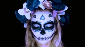 Closeup face of woman with Mexican sugar skull makeup and flowery wreath opening eyes and looking into the camera. Creative, artistic, Halloween concept - slow motion video - Powered by Shutterstock - Get 15% off with code: PIKWIZARD15