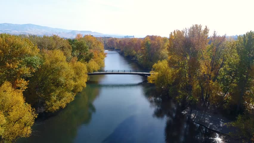 Foot Bridge crosses the Boise River with fall colored trees and city