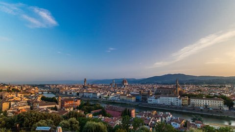 Top view of Florence city timelapse at sunrise with arno river bridges and historical buildings, mountains on background. Green trees, blue cloudy sky at summer day
