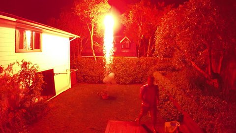 Adult man launching fireworks explosive pyrotechnic at home back yard.  Real people. Copy space