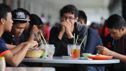 IPOH, MALAYSIA - NOVEMBER 04, 2017. Group of Malay teenager talking each other as they enjoy their meal at the food court in Ipoh, Perak.