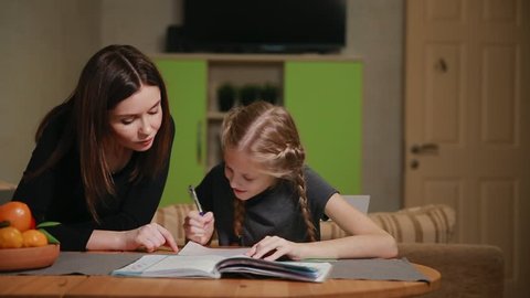 Mother and daughter doing a school homework assignment. Mom helps to deal with it.