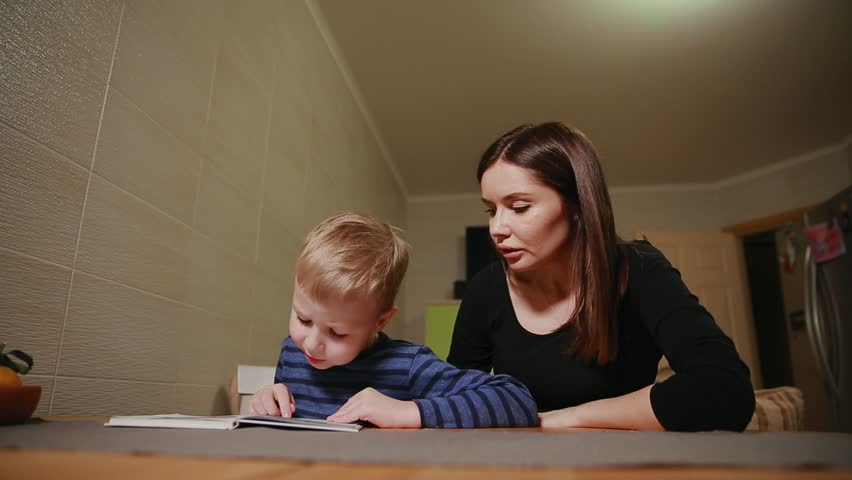 Mother and son sitting in the kitchen of his house and learning to read book. | Shutterstock HD Video #32483680
