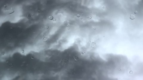 Animated rotating camera shooting upward at a cloudy sky while raining, drops of water collecting on the glass to form a red heart shape symbol - Βίντεο στοκ