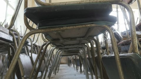 Rows of old chairs stacked on top of each other in an abandoned restaurant, public dining room, conference room. Underside view