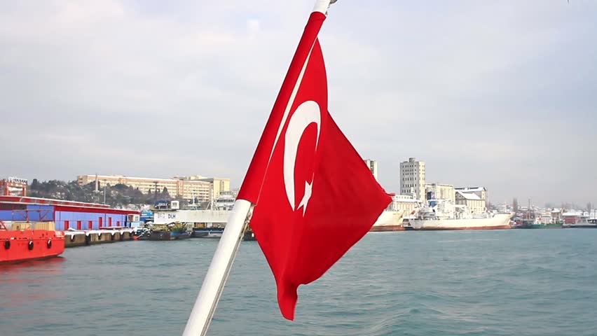 Seaport as seen from the waterside with a Turkish Flag waving. A tugboat moored