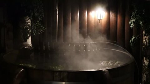 Wooden bath filled with hot water and branches in a bath, slow motion