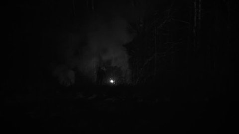 Silhouette of a man chased by light through the forest at winter night