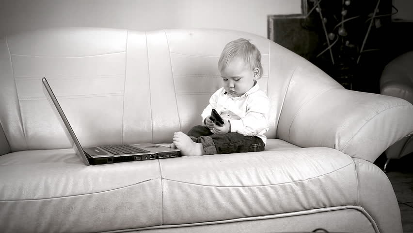 Child sitting on sofa and looks in laptop 