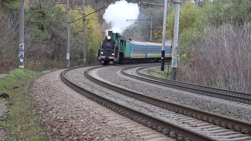 A steam locomotive moving forward and signaling with a steam whistle.