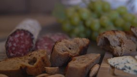 on the table lay the slices of the sausage and the loaf of servilda. In the background a quarter of cheese with green mold and sliced pieces of baguette from rye flour. appetizing video. Panoramic