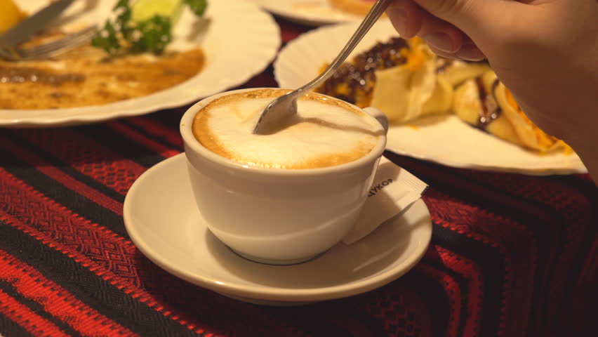 Slow motion. white cup of coffee with thick foam. cappuccino. the man stirs slowly with a spoon. It raises a teaspoon and drips coffee and foam into the mug.