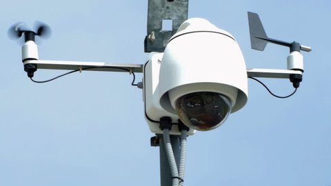 Security Cameras. Closeup video surveillance system, vane and anemometer, with blue sky background. Front view.