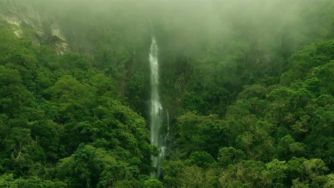 Epic waterfall Nature background full hd and 4k. High Humidity In Jungle Rainforest with a powerful waterfall. Timelapse Of Moving Clouds And Fog over a waterfall between Green mountains. Ecology.