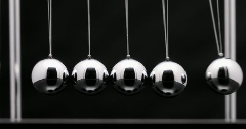 Newton's cradle office toy. Studio shot of swinging metal balls in slow motion on black background