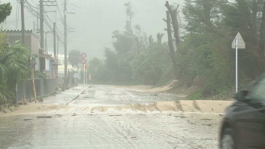 OKINAWA, JAPAN - AUGUST 2012: Car drives along road covered in sand after
