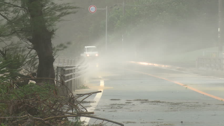 OKINAWA, JAPAN - AUGUST 2012: Car drives along road during typhoon Bolaven.
