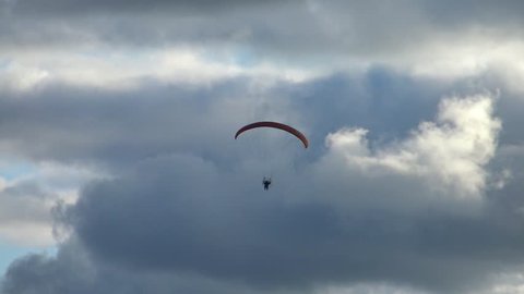 Paraglider flying high in the storm clouds. Air sport and recreation. A powered paraglider - a glider with a dorsal power plant, providing the rise and moving in the air. 
